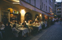 Lyon.  People eating at outside tables in street side restaurants in evening.