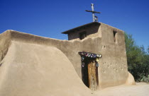 De Grazias Mission church exterior with plain sandstone walls and floral decoration around the doorway.