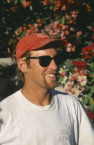 Single American man  in baseball cap and sunglasses  head and shoulders three-quarter profile right.