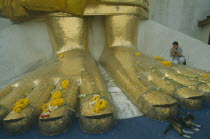 Banglamphu. Wat Indravitham. Woman praying at the feet of  Golden Buddha.