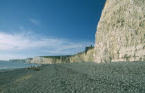 Occupied peeble beach and long section of cliff face.