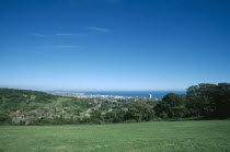 Elevated view from the South Downs over fields towards town and coastline.