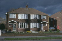 Semi detached housing with a single car parked in the driveway.