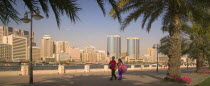 View of Deira across Dubai Creek from Bur Dubai. A couple holding hands and palm trees in the foreground.Travel  Tourism  Panorama  Dubayy United Arab Emirates