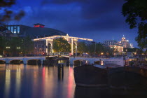 Magere Brug  Skinny Bridge  at dusk with The Koninklijk Theater Carre behind.Holidays  Tourism  Travel  Canals Bridge  Theatre  Netherlands.