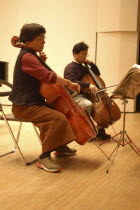 53 year old public health nurse named Teruko Ui plays cello with teacher Satoshi Miyano  at recital as a hobby and for relaxation