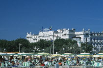 The Grand Hotel with busy beach  parasols and sun loungers in the foreground.