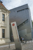 Visitors walking past entrance to the Jewish Museum designed by Polish architect Daniel Libeskind in 1998 with name sign in foreground.