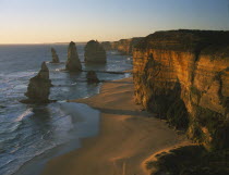 Great Ocean Road. View along the beach and cliffs toward The Twelve Apostles sea stacks in warm evening light