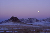 Mountains lightly covered in snow at sunset with pink sky.  Taken in March