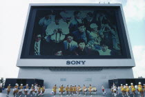 Exhibition of Technology with view of Sony Jumbotron massive Television screen and girls marching with pom poms in foreground.Tokyo Ex 1985