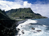 Hermigua.  Coastal landscape with narrow beach of black volcanic sand and village houses on steep terraced hillside.