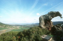 Italy, Sardinia, Near Castelsardo. View of Elephant Rock in landscape over looking fields and hills with a road passing through.