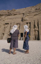 Two female tourists wearing head scarves in front of staues of Ramesses II at the temple entranceSun protection