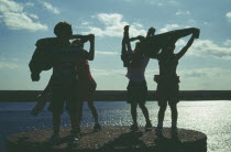 Kids playing on quayside silhoetted against the sky