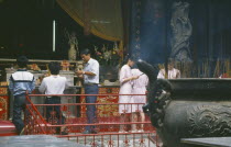 People making offerings of incense at temple.