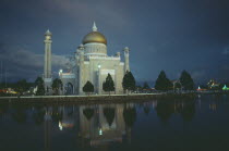 Omar Ali Saifuddin Mosque  exterior view reflected in water illuminated at dusk.