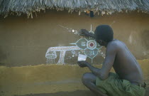 Dinka man decorating house in refugee camp.