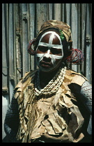 Portrait of Kikuyu tribeswoman with painted face and wearing head dress for initiation ceremony.