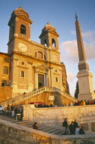 Trinita dei Monti sixteenth century church at the top of the Spanish Steps at sunset with tourist crowds.