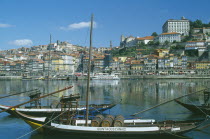 The River Douro and waterside buildings with port barges or barcos rabelos moored in the foreground. Porto