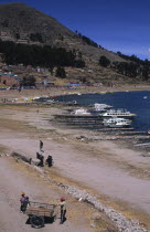 Lake side scene with boats and people.