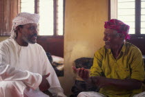 Discussioin between two Omanis  including traditional fisherman on the right hand side.