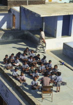 School children receiving their class on top of a roof.