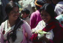 Two indegenous women smiling  one holding sweetcorn.