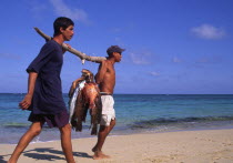 Fishermen with freshly caught fish on a beach.