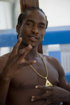 Water taxi driver from Canouan wearing golden medallion at the Easterval Easter Carnival making a rap gesture with his fingers