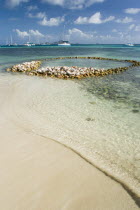 Conch shell structures on the beach at Clifton Harbour with yachts moored behind