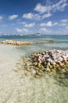 Conch shell structures on the beach at Clifton Harbour with yachts moored behind