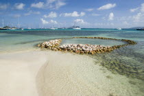 Conch shell structures on the beach at Clifton Harbour with yachts moored behind