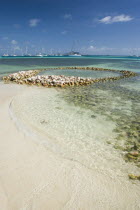 Conch shell structures on the beach at Clifton Harbour with yachts moored behind