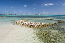 Conch shell structures on the beach at Clifton Harbour with yachts moored behind