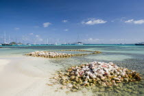 Conch shell structures on the beach at Clifton Harbour with yachts moored behind