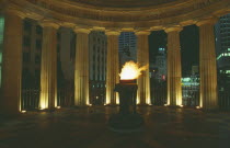 Anzac memorial  flame illuminating surrounding columns at night.