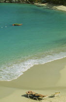 Man sunbathing on sun lounger by the water s edge