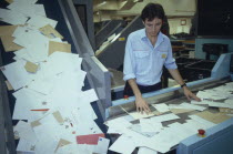 Mail sorting office.  Male worker sorting through letters on conveyor belt to culler.