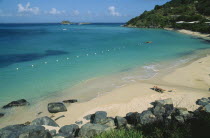 Wide view of the bay with man sunbathing on sun lounger by the water s edge