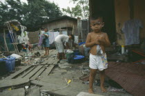 Klong Toey. Child standing by women hanging washing in slum housing area