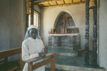 Young nun praying in front of altar inside mission.