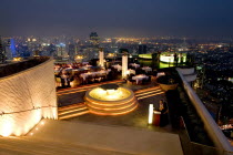 Sorocco Restaurant. View down steps towards people dining at tables lit up with light displays and the Bangkok Skyline in the background.Taken from the State Tower the 2nd tallest building in Bangkok