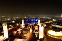 Sorocco Restaurant. View over people dining at tables lit up with light displays and the Bangkok Skyline in the background.Taken from the State Tower the 2nd tallest building in Bangkok