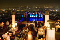 Sorocco Restaurant. View over people dining at tables lit up with light displays and the Bangkok Skyline in the background.Taken from the State Tower the 2nd tallest building in Bangkok