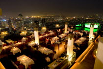 Sorocco Restaurant. View over people dining at tables lit up with light displays and the Bangkok Skyline in the background.                Taken from the State Tower the 2nd tallest building in Bangk...