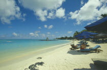 The beach at the Mauritius Hotel. People on sun loungers  and umbrellas.