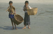 Two young boys carrying large woven baskets.