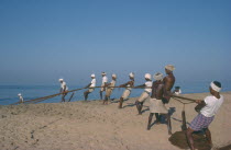 Fishermen on beach pulling in nets.Kerela Kovalum